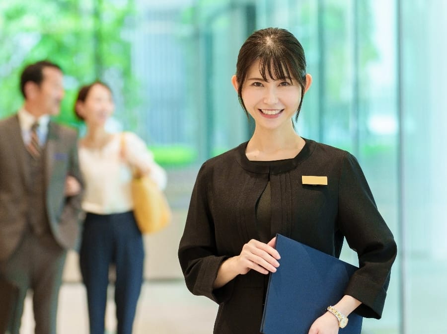 資料を持って立つスーツの女性